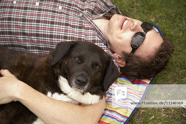Caucasian man laying in park with dog