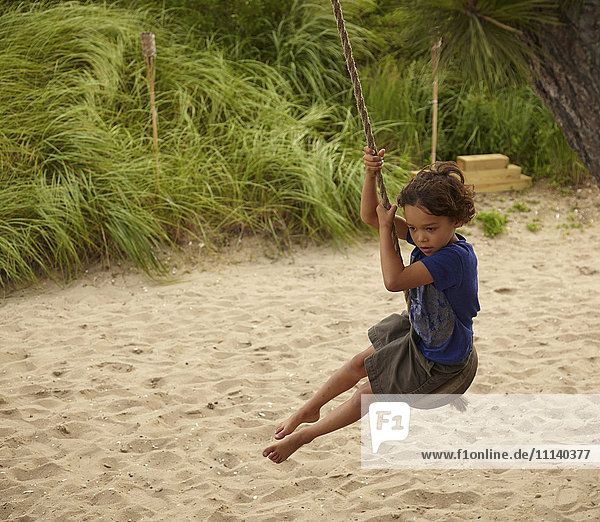 Mixed race boy playing on swing