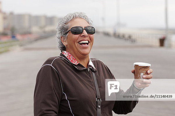 Smiling woman drinking coffee on boardwalk