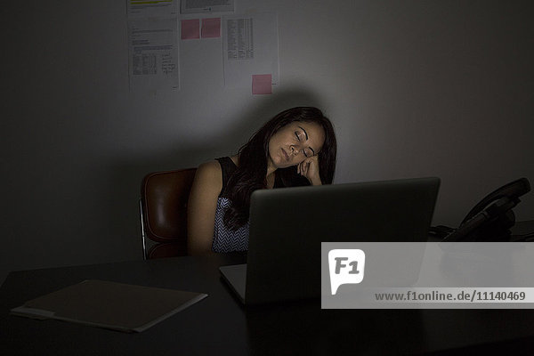Geschäftsfrau schläft nachts am Schreibtisch