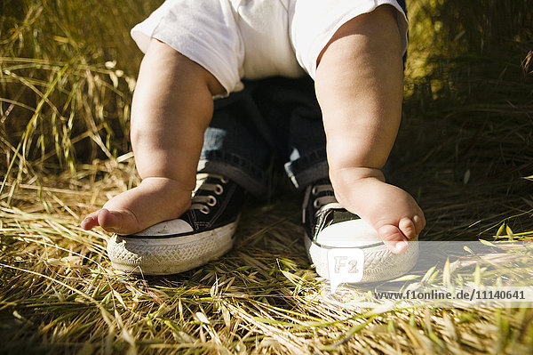 Die Füße des Babys auf den Füßen des Vaters