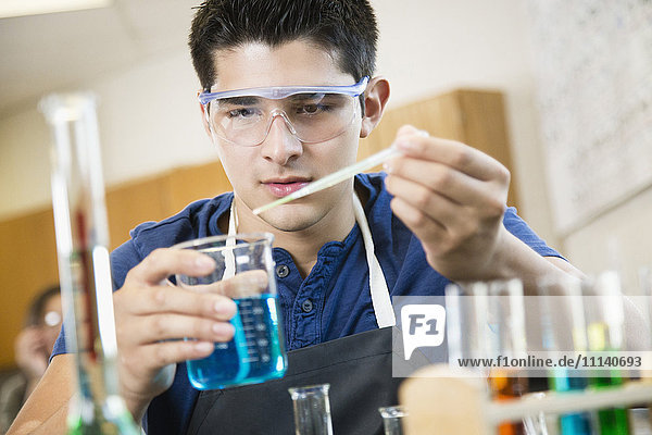 Hispanischer Schüler arbeitet mit Chemikalien im Klassenzimmer