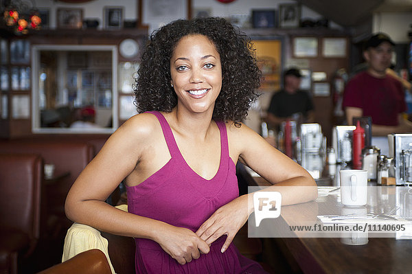 Lächelnde afroamerikanische Frau  die an der Theke eines Diners sitzt