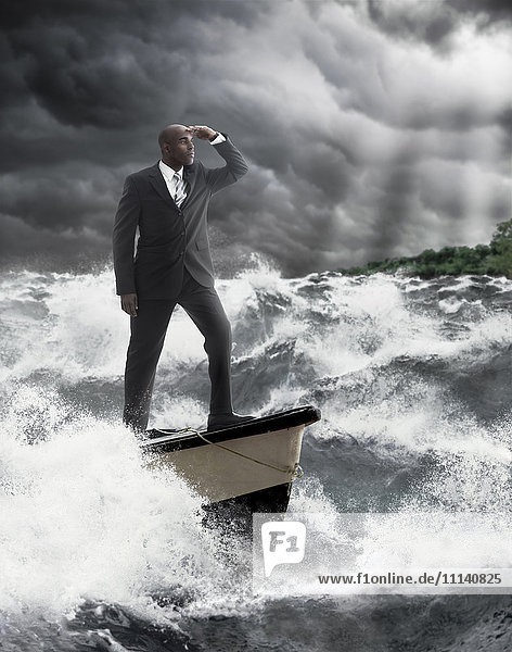 African American businessman standing at helm of boat on stormy sea