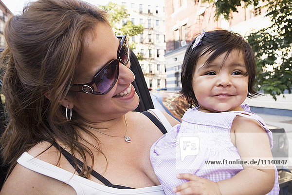 Lächelnde hispanische Mutter und Tochter auf einer städtischen Straße