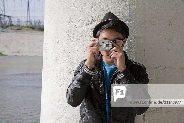 Mixed race teenage boy taking photograph with digital camera