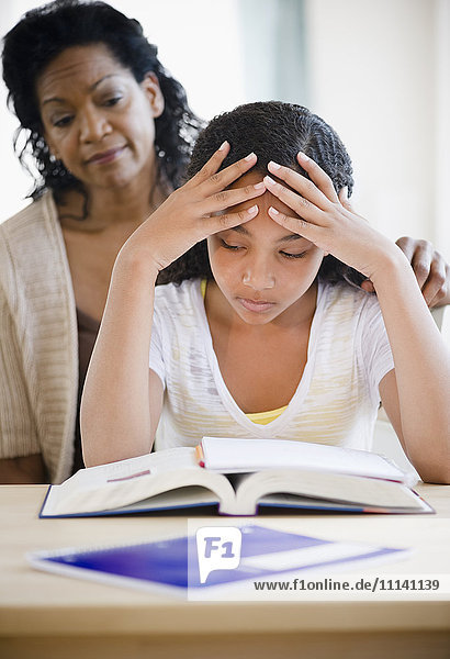 Mutter tröstet frustrierte Tochter bei den Hausaufgaben