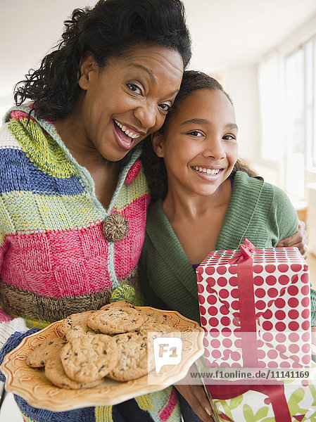 Mutter und Tochter tragen Geburtstagsgeschenk und Kekse