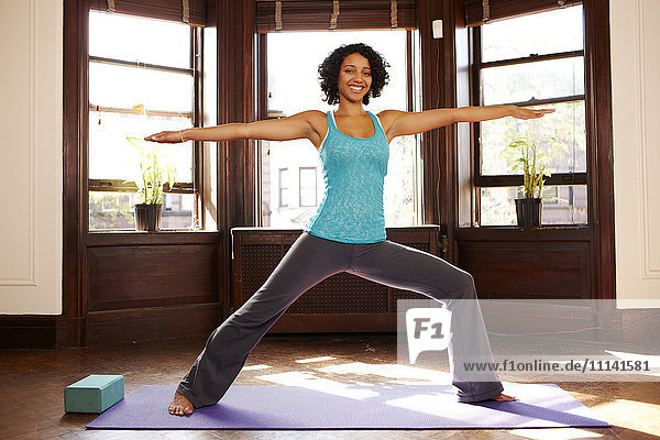 Mixed race woman practicing yoga in living room