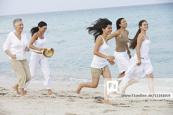 Unterschiedliche Frauen laufen gemeinsam am Strand