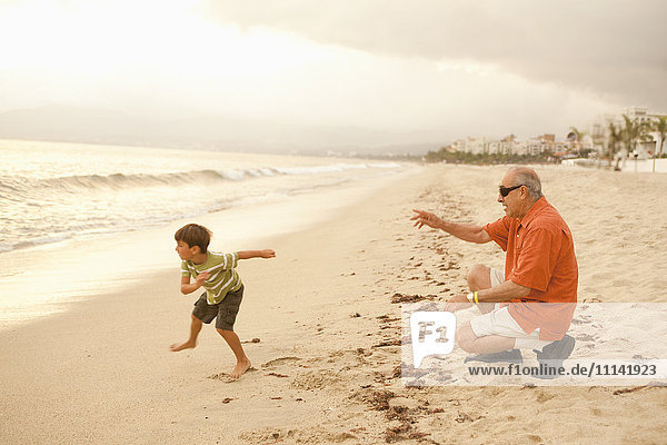 Grandfather and grandson playing on beach together