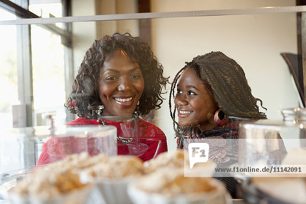 Schwarze Mutter und Tochter betrachten Gebäck in einem Cafe