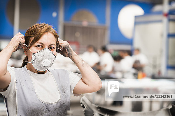 Arbeiter mit Gesichtsmaske in einer Produktionsstätte