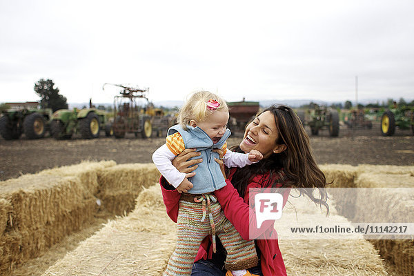 Mother and daughter enjoying playing on hay bales