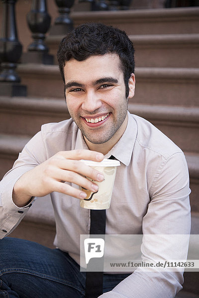 Hispanischer Geschäftsmann trinkt Kaffee auf der Treppe