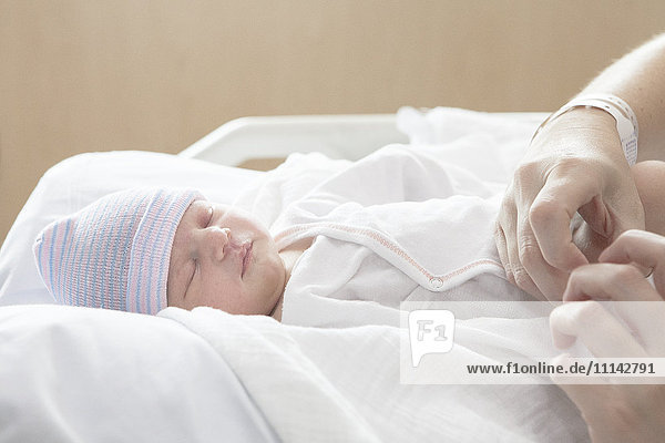 Kaukasische Mutter hält ihre neugeborene Tochter im Krankenhausbett