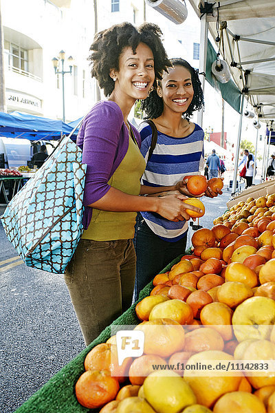 Frauen kaufen gemeinsam am Obststand ein