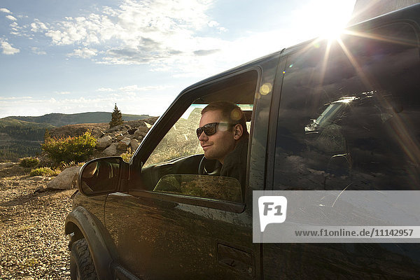 Man sitting in car overlooking rural landscape