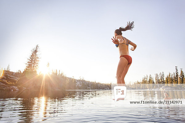 Woman jumping into rural lake