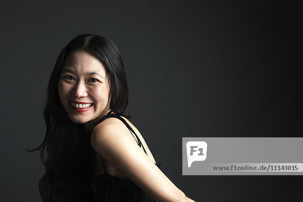 Asiatische Frau lächelt über ihre Schulter