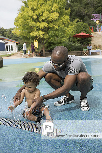 Vater und Kleinkind spielen im Springbrunnen