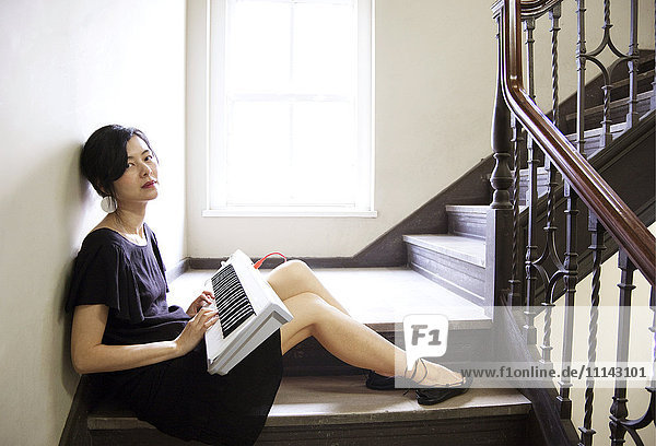 Taiwanesische Frau spielt Keyboard auf einer Treppe