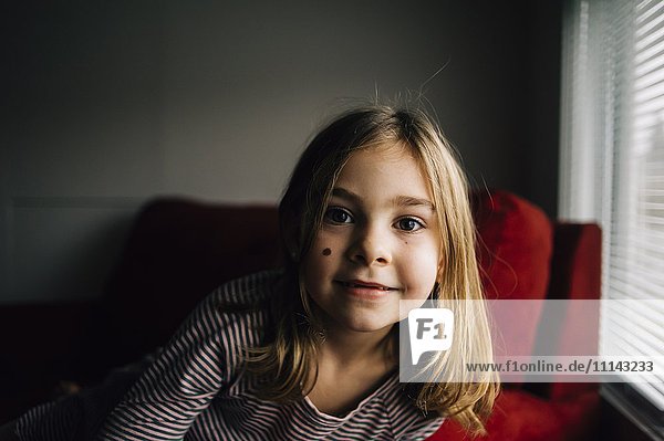 Smiling girl sitting in armchair