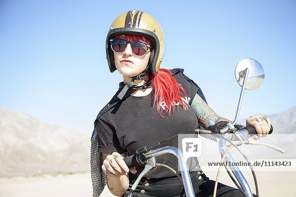 Frau auf Motorrad in der Wüste sitzend