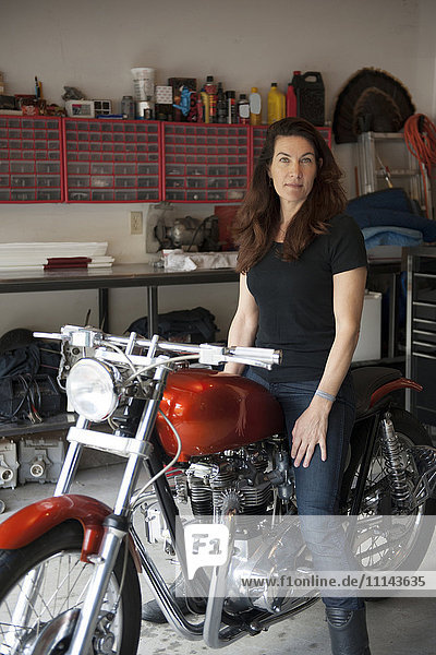 Frau sitzt auf Motorrad in Garage