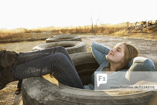 Kaukasisches Teenager-Mädchen sitzt in einem leeren Reifen
