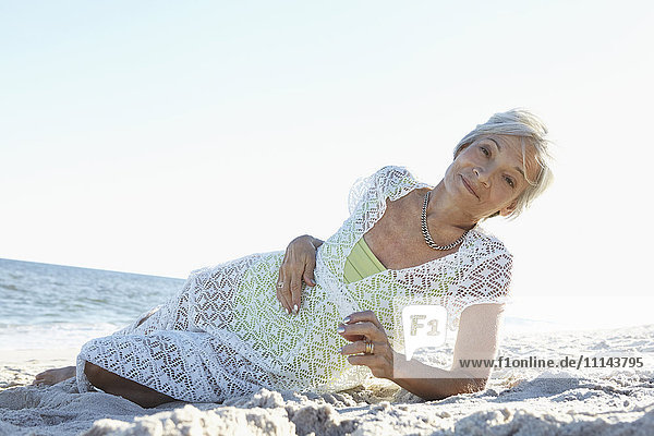Ältere Frau liegt am tropischen Strand