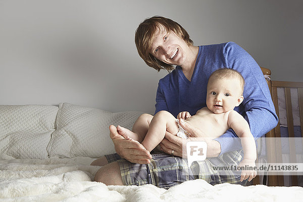 Father holding baby on bed