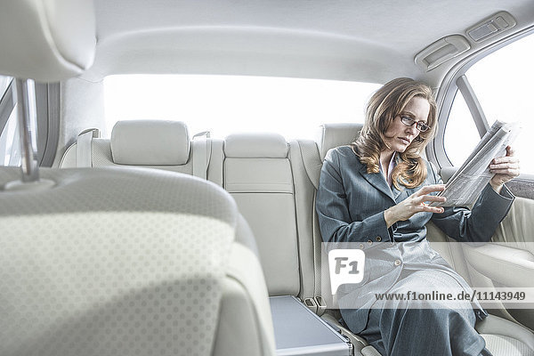Geschäftsfrau liest Zeitung im Auto