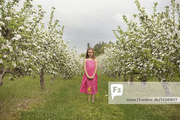 Kaukasisches Mädchen in blühendem Obstgarten stehend