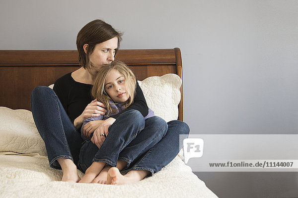 Kaukasische Mutter kuschelt mit ihrer Tochter auf dem Sofa