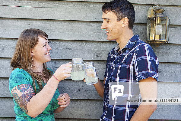 Couple toasting with drinks near wall