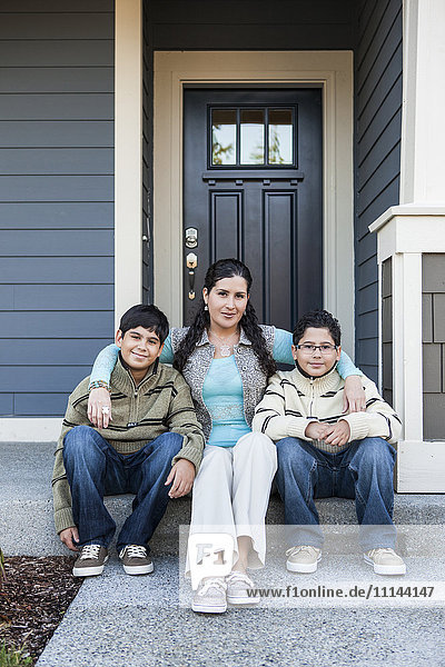 Hispanische Mutter und Söhne sitzen auf der Treppe