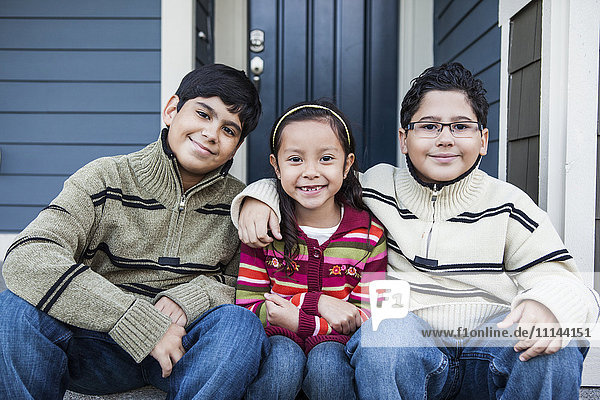 Gemeinsam lächelnde Kinder auf der Treppe vor dem Haus