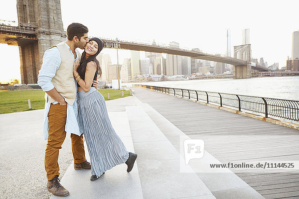 Indian couple kissing by bridge  New York  New York  United States