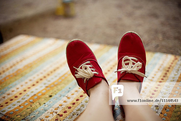Red sneakers of Caucasian on rug