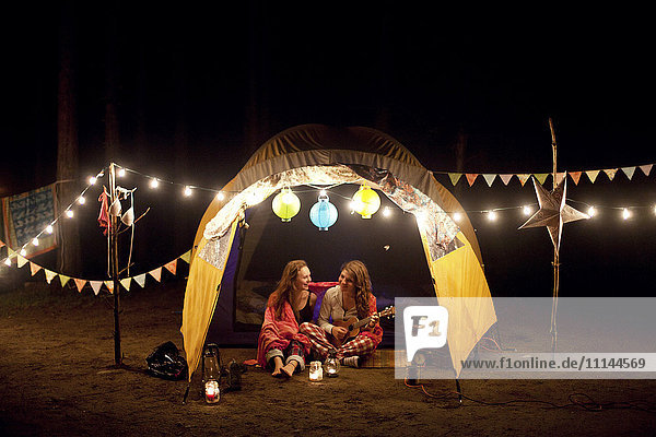 Girls relaxing in camping tent at night