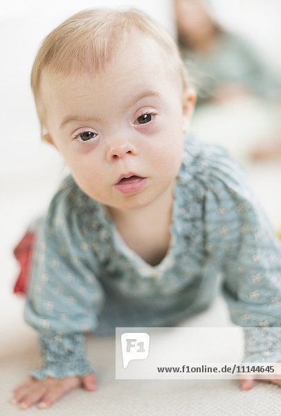 Caucasian baby girl with Down Syndrome crawling
