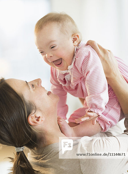 Caucasian mother playing with baby girl with Down Syndrome
