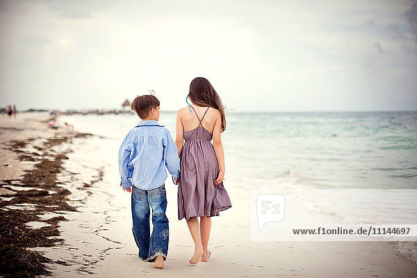 Brother and sister walking on beach
