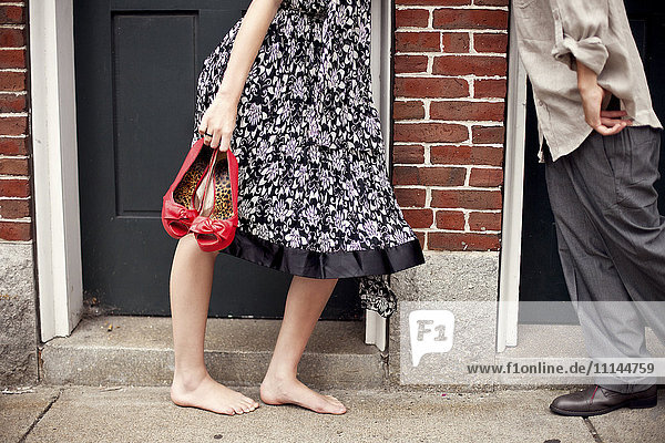 Barefoot girl holding shoes near boyfriend in doorway