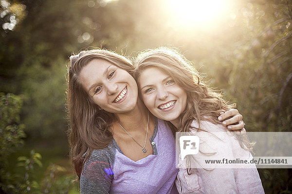 Smiling women hugging in rural field