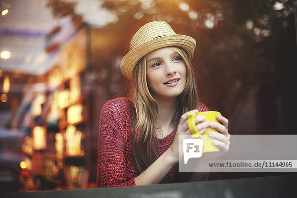 Girl drinking coffee in cafe near window