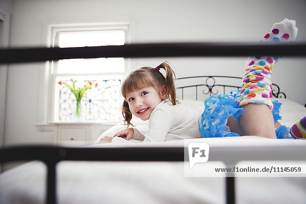 Lächelndes Mädchen spielt auf dem Bett
