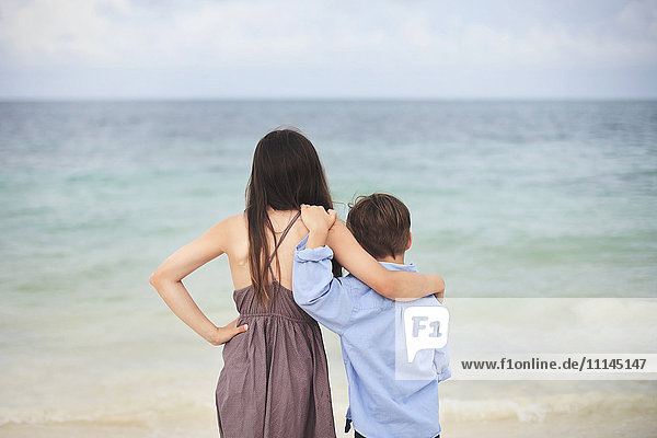 Brother and sister hugging on beach