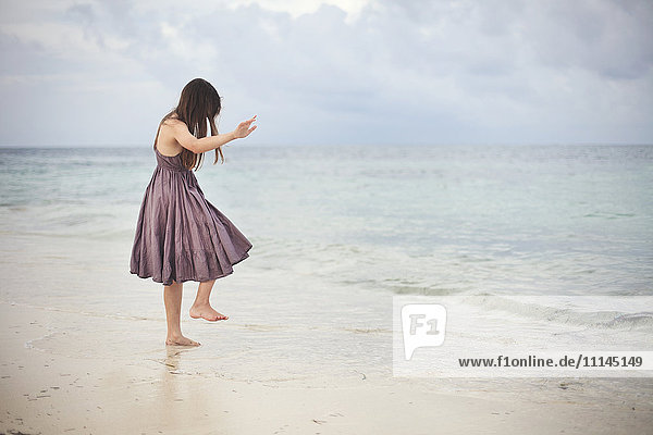 Mädchen tanzt in den Wellen am Strand